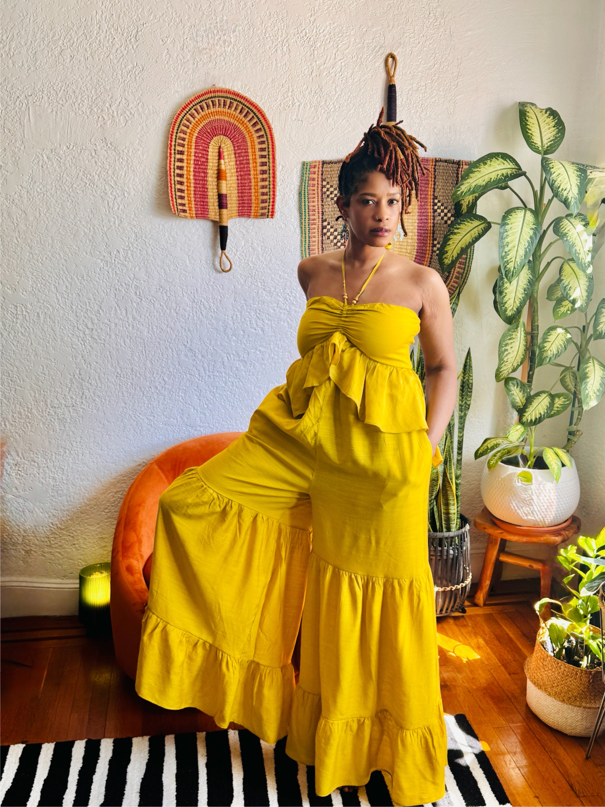 Model wearing the Butterfly Ruffle Romper in mustard linen, featuring halter neckline and dramatic ruffle details.”