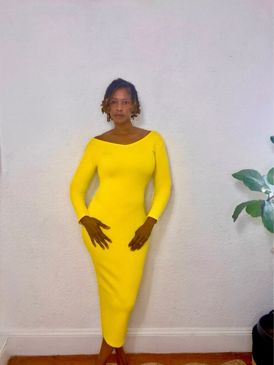 Model posing against a white wall in the yellow midi dress, highlighting the sculpted fit.