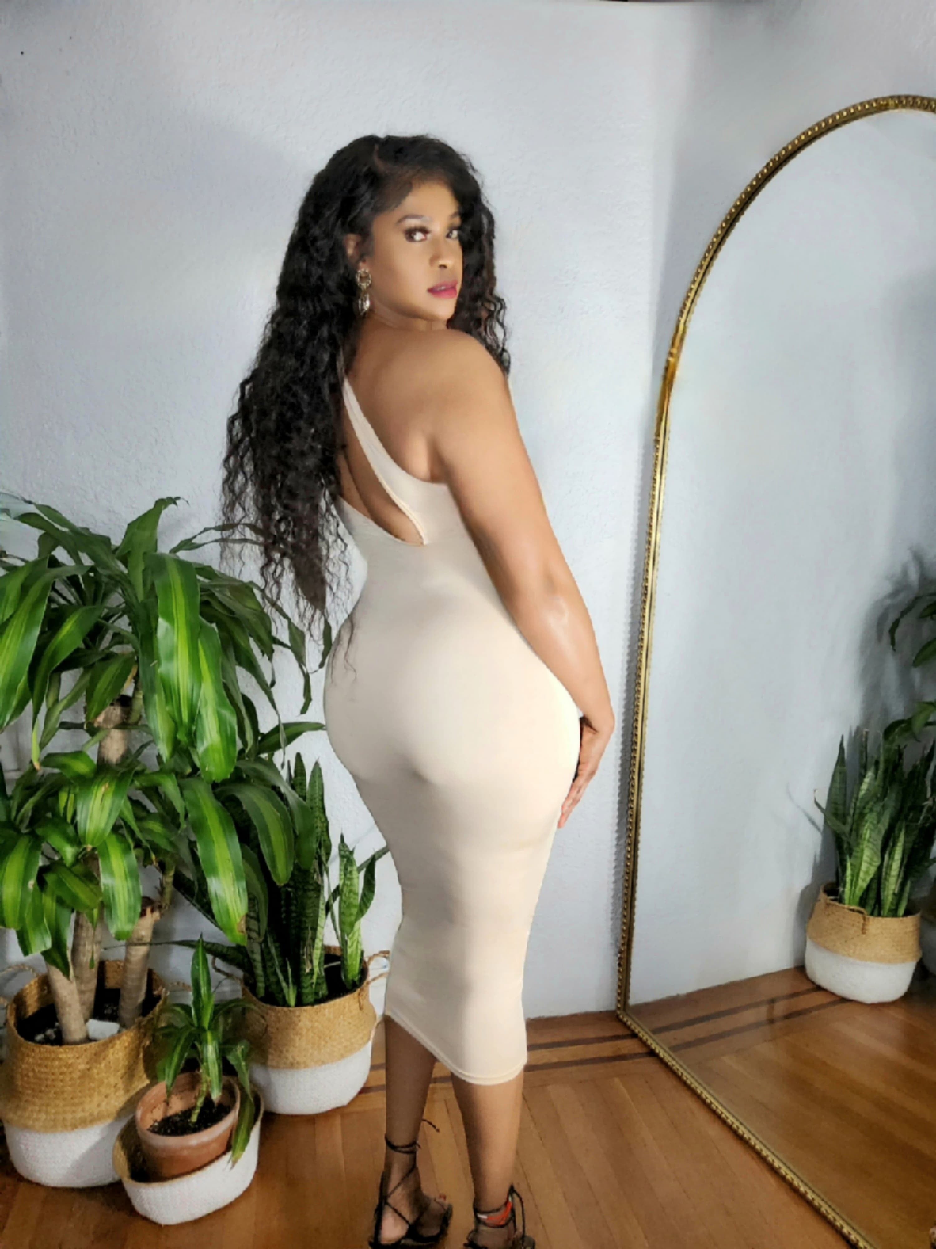 Woman wearing the Satin Temptress Dress in black satin with one-shoulder cutout.