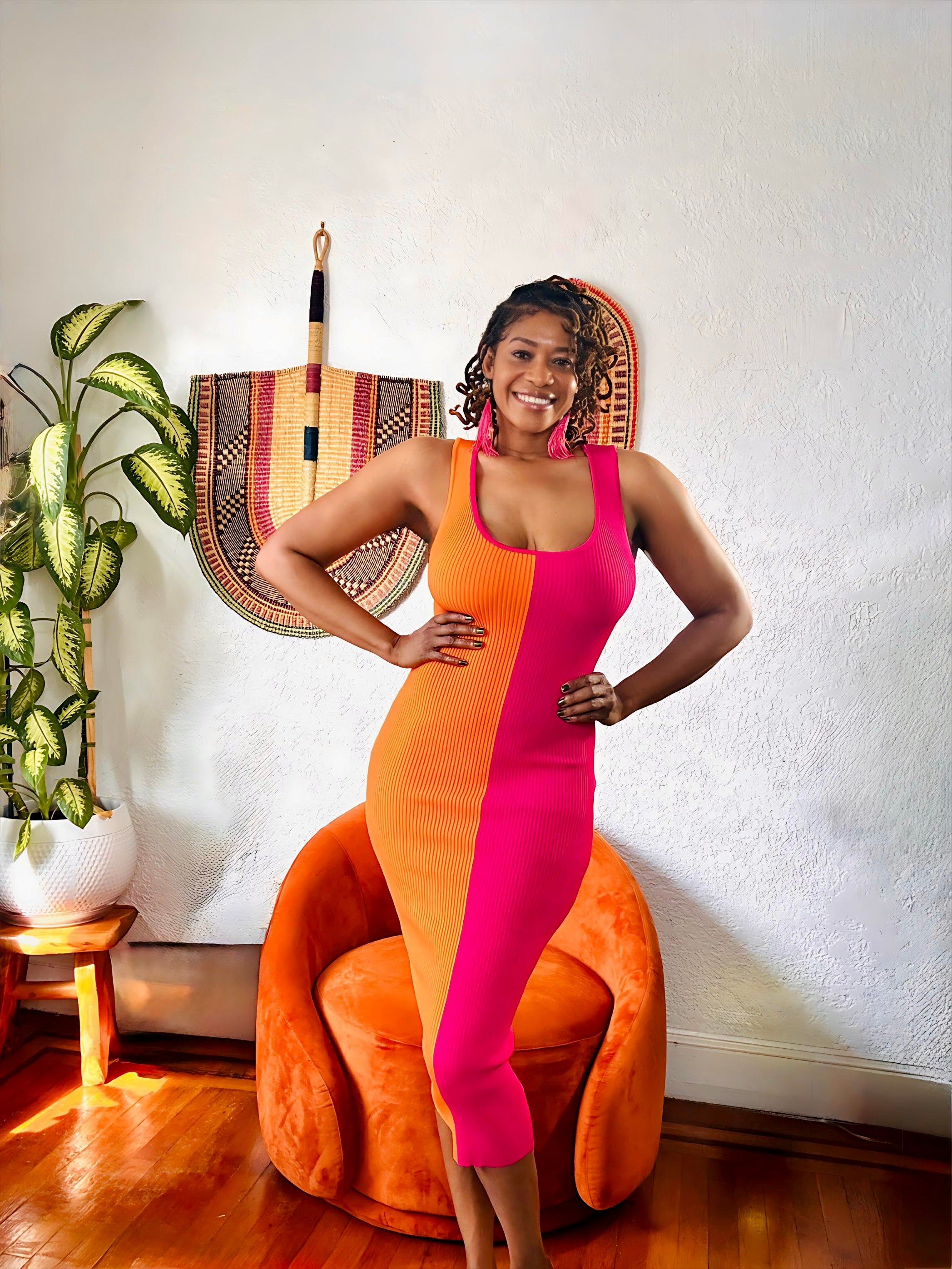 Full-length view of orange-and-pink midi dress styled with earrings and heels.